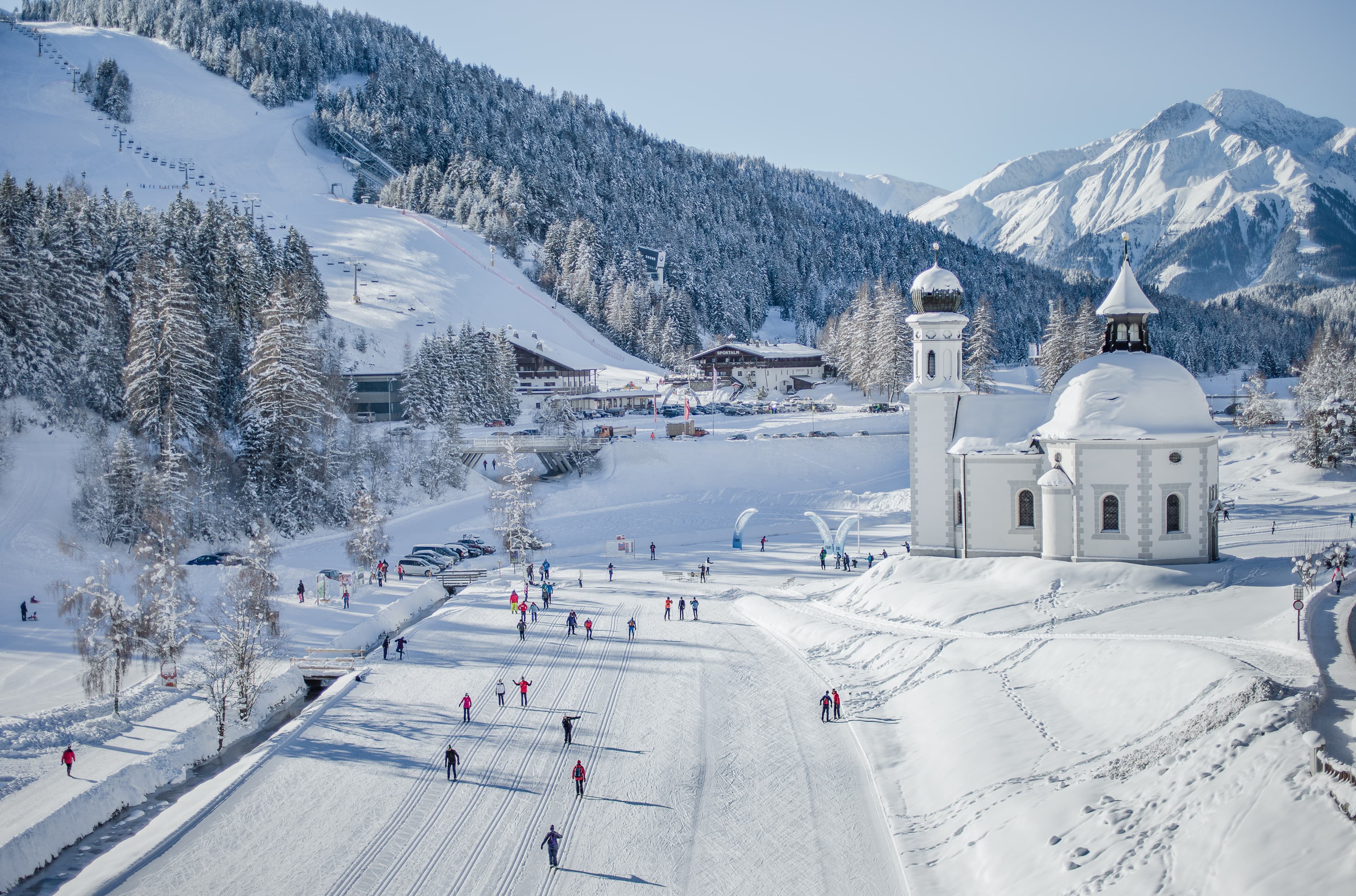 Skiiers skiing past traditional church in Seefeld ski resort